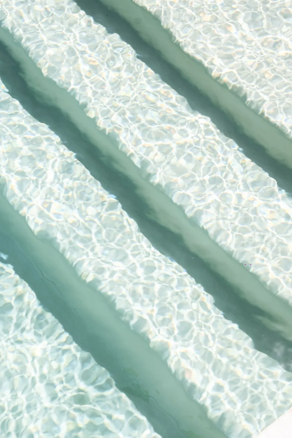 Close-up of sunlight rippling over the submerged steps of the pool, an abstract of water and caustics