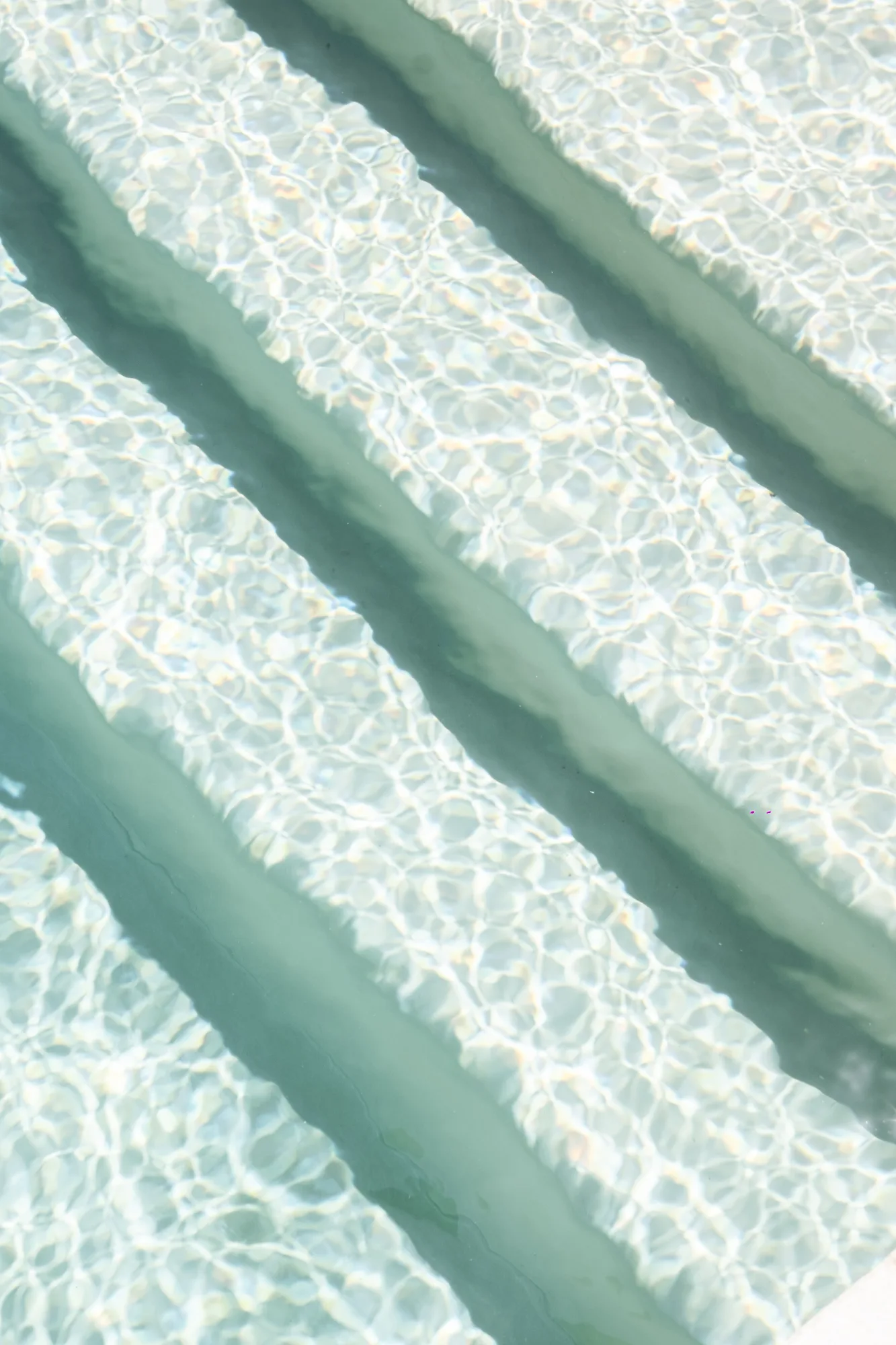 Close-up of sunlight rippling over the submerged steps of the pool, an abstract of water and caustics