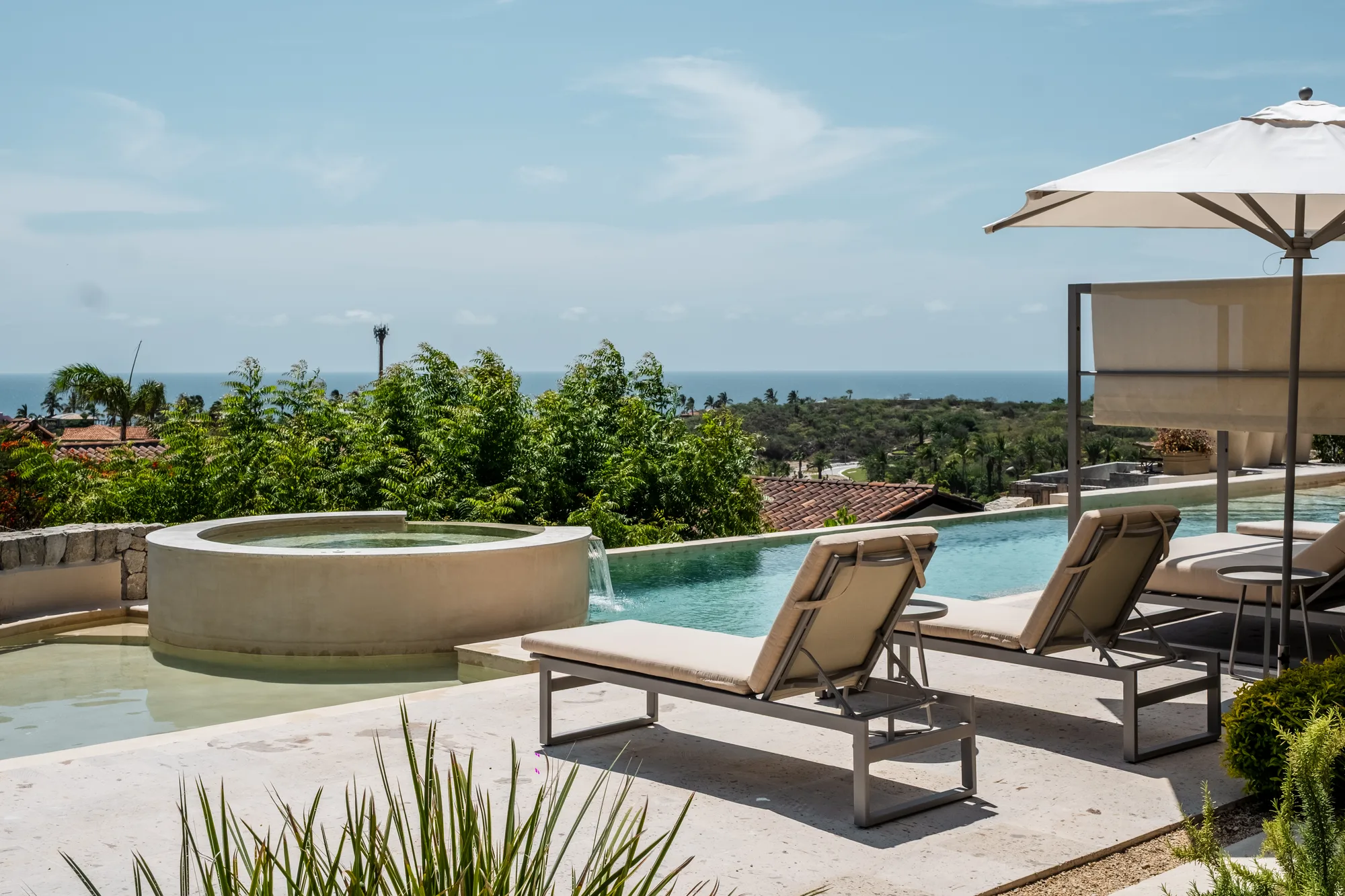 Sun loungers beside the infinity pool and round spa, with the sea on the horizon