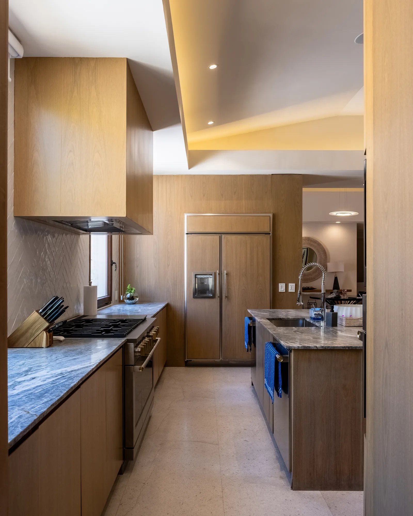 Chef's kitchen with blue granite counters, a gas range and hood, and a built-in refrigerator in wood cabinetry
