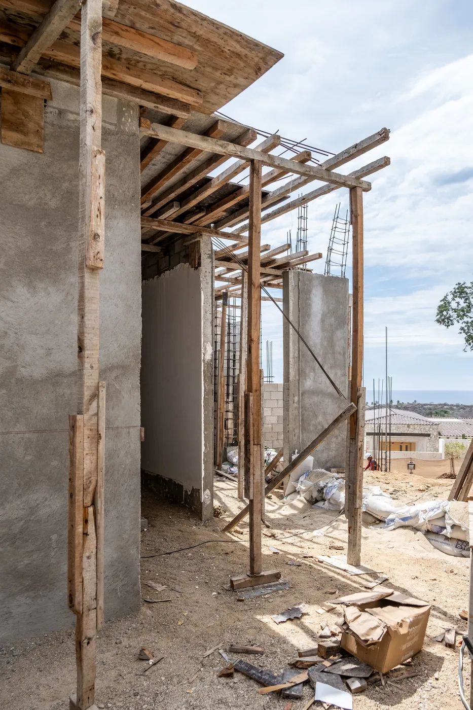 Corner of concrete walls braced by timber shoring under a slab, with the sea visible in the distance
