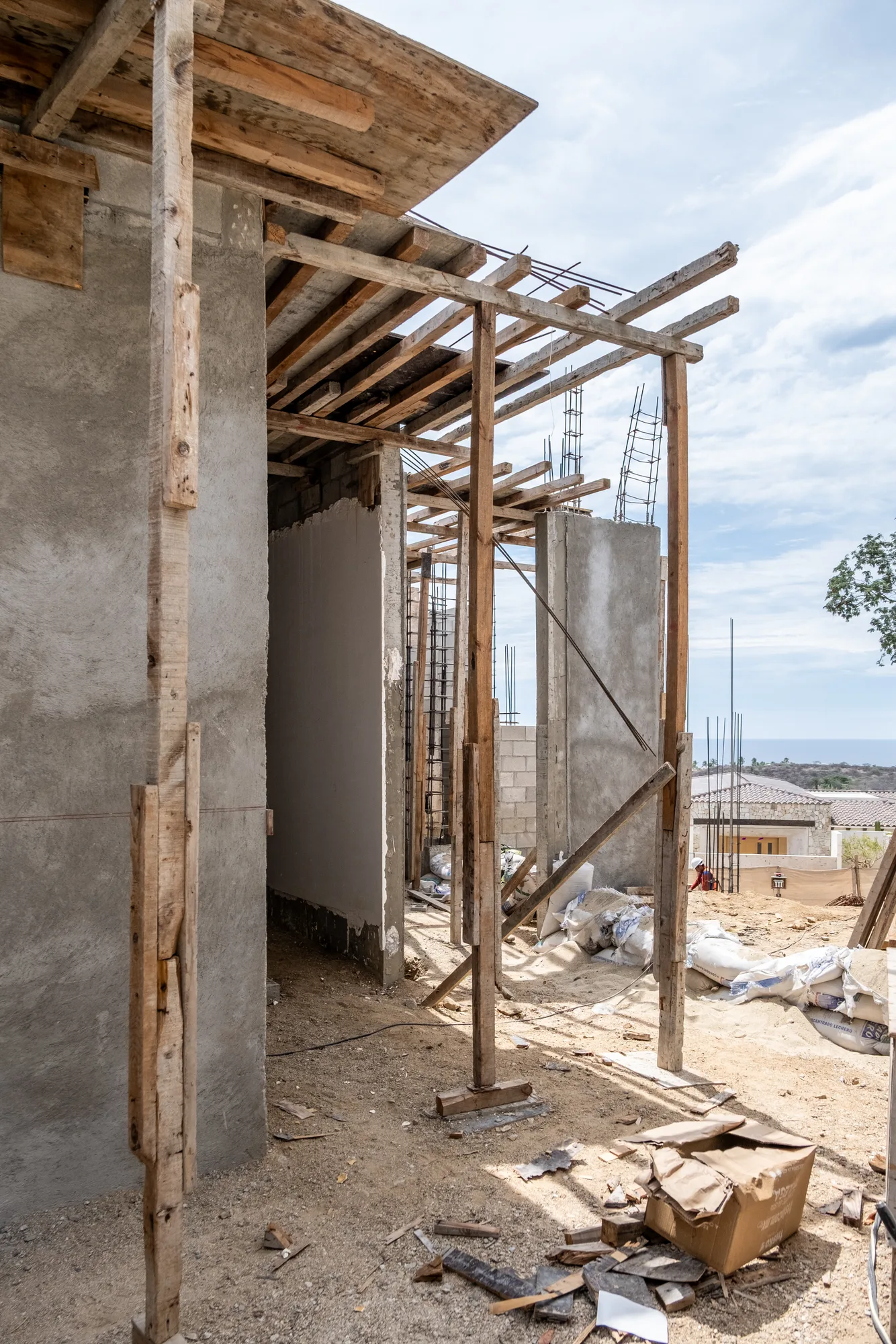 Corner of concrete walls braced by timber shoring under a slab, with the sea visible in the distance