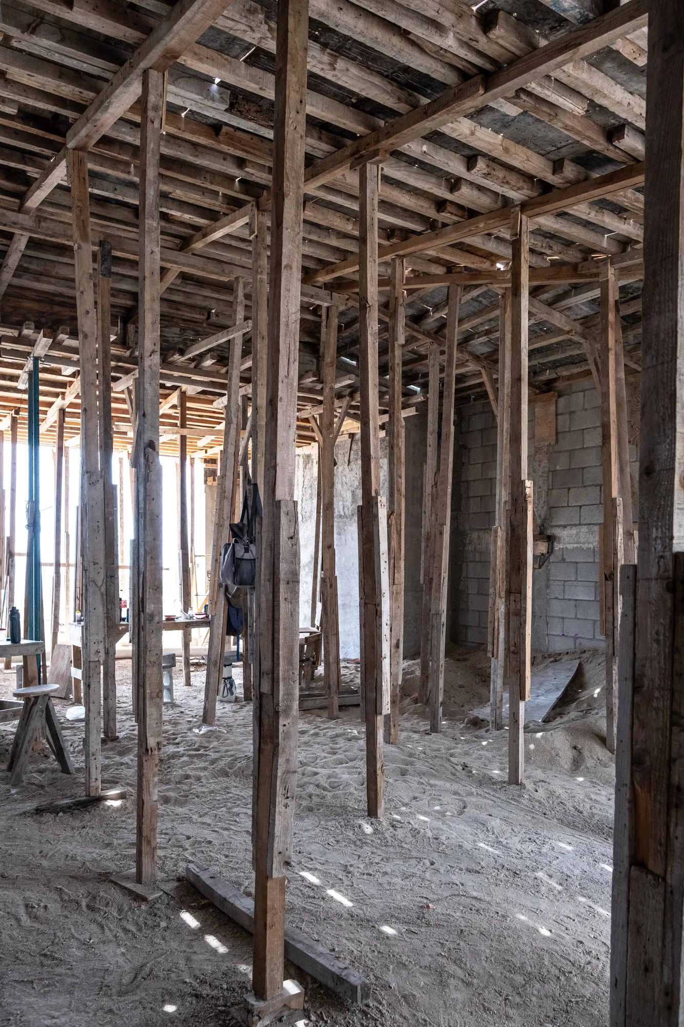 Interior filled with timber shoring posts holding up the floor slab above, light falling on the sandy ground