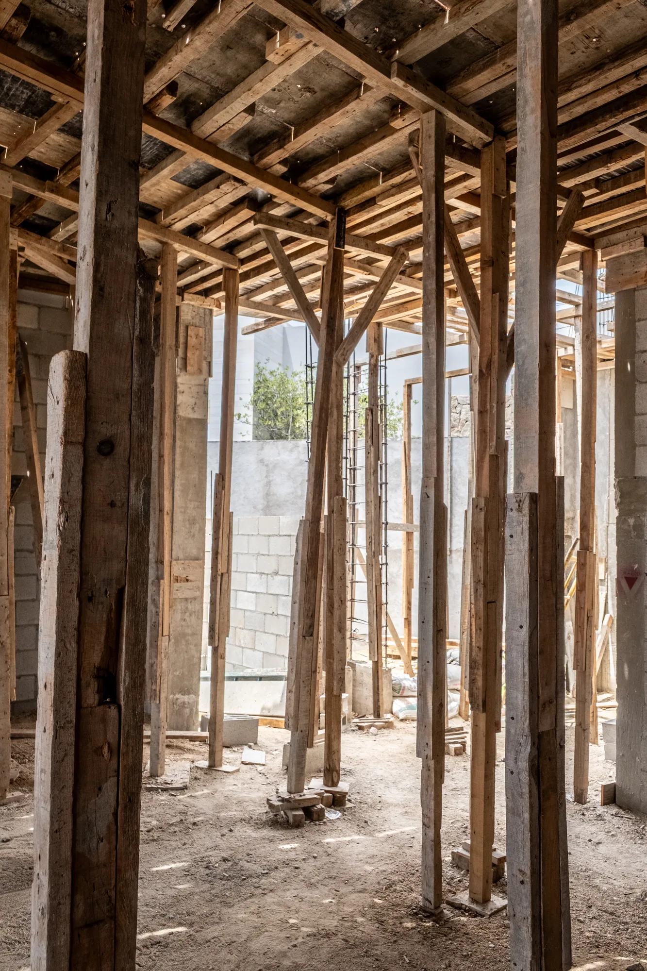Interior forest of timber props under the formwork, with a branching shore, block walls and a stair beyond