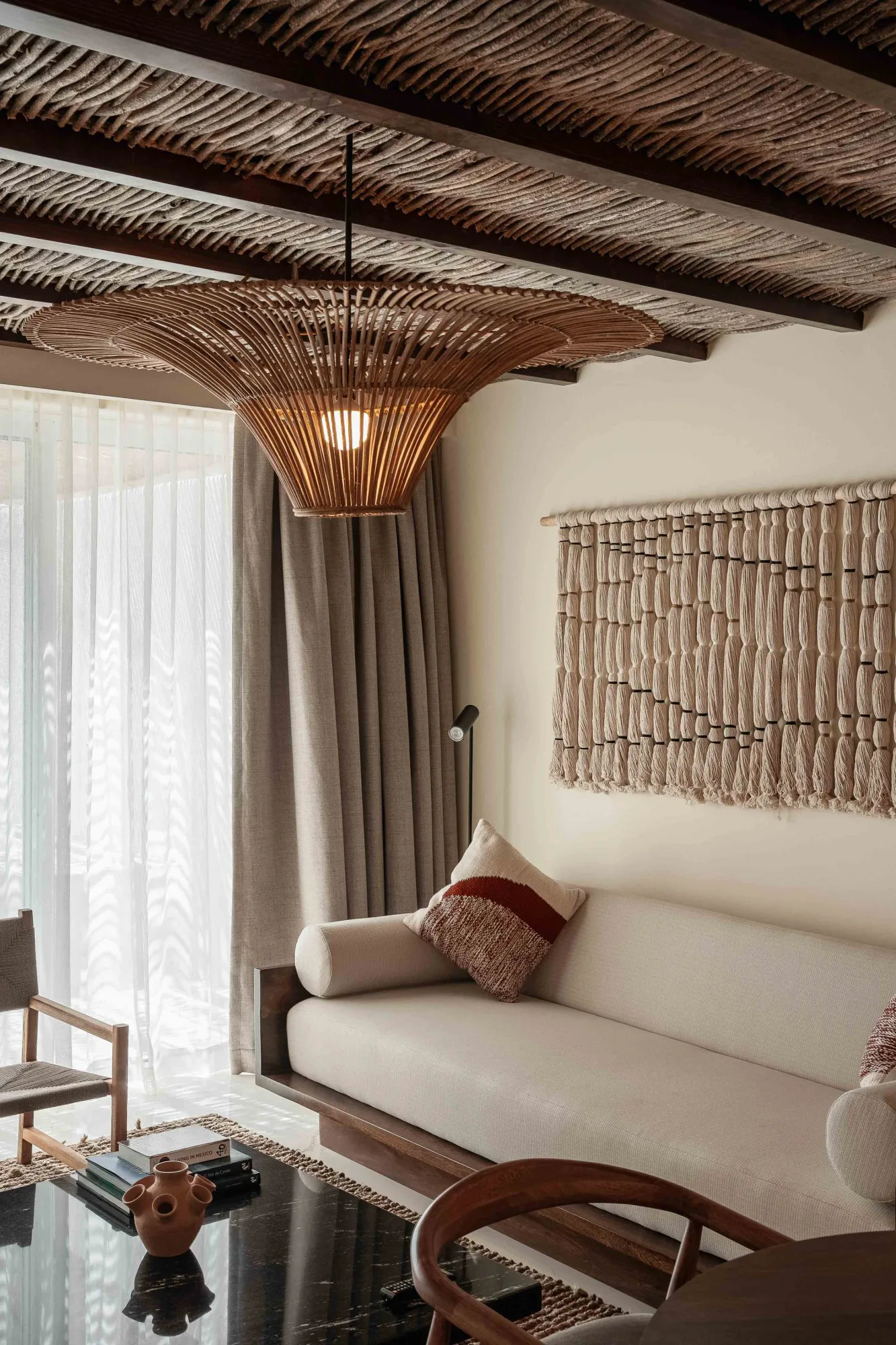 Suite lounge with a woven reed ceiling on dark beams, a large rattan pendant, a white sofa and a macramé wall hanging, Hotel Indigo in La Paz